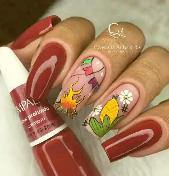 Unhas decoradas com elementos típicos da Festa Junina, como fogueira, bandeirinhas e milho.