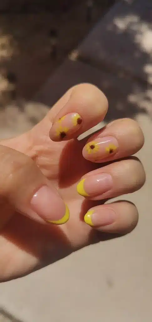 Unhas decoradas com flores amarelas delicadas e pontas amarelas vibrantes