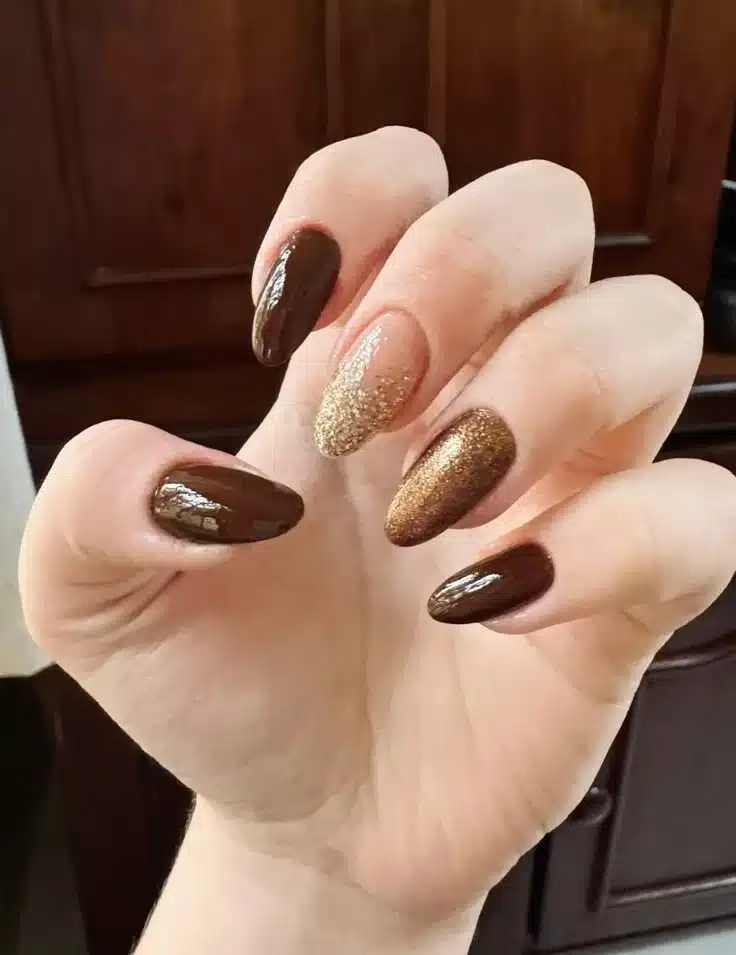 Unhas decoradas com esmalte marrom e detalhes em glitter dourado e bronze