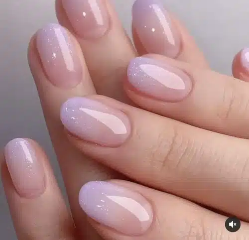 Unhas com acabamento delicado e brilhante em tom lilás suave, com efeito minimalista e elegante.