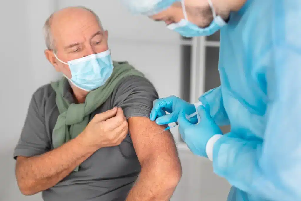 Homem idoso recebendo vacina no braço, protegendo sua saúde na terceira idade