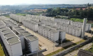 Vista aérea de conjunto habitacional com prédios brancos do programa Minha Casa, Minha Vida