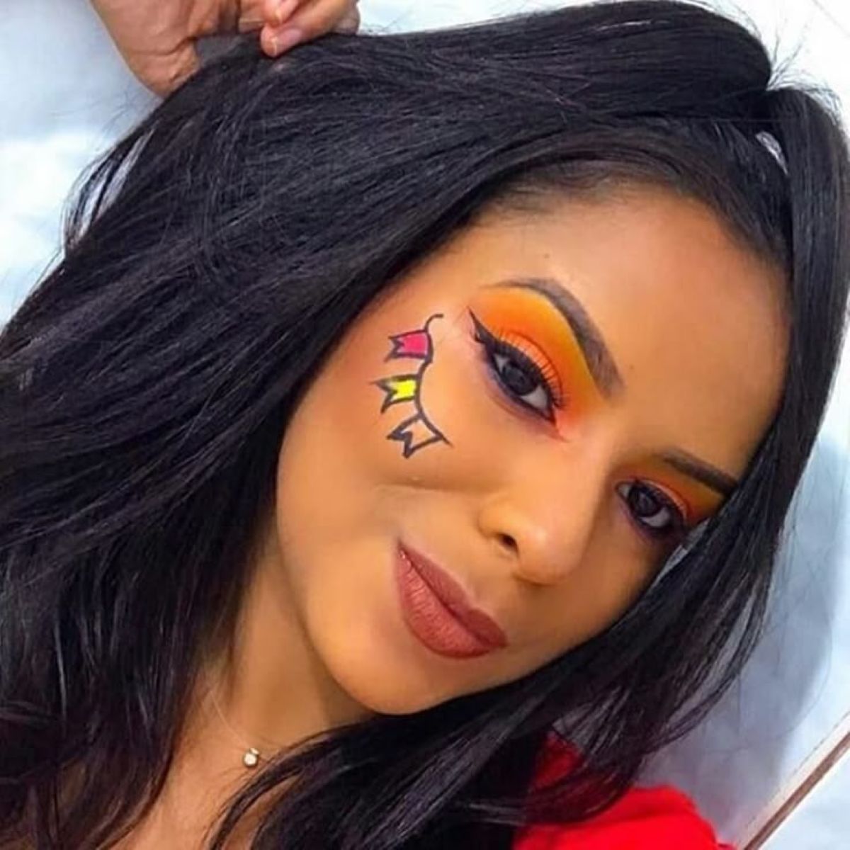 Maquiagem junina com delineado criativo e bandeirinhas coloridas desenhadas no rosto, perfeita para festas de São João.