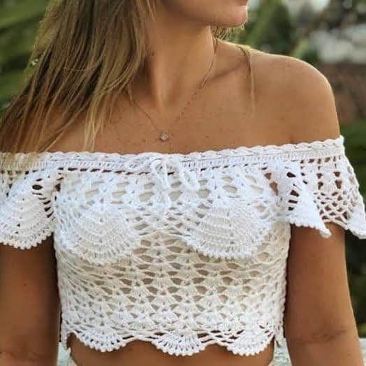 Mulher usando blusa ciganinha de crochê branca com detalhes delicados