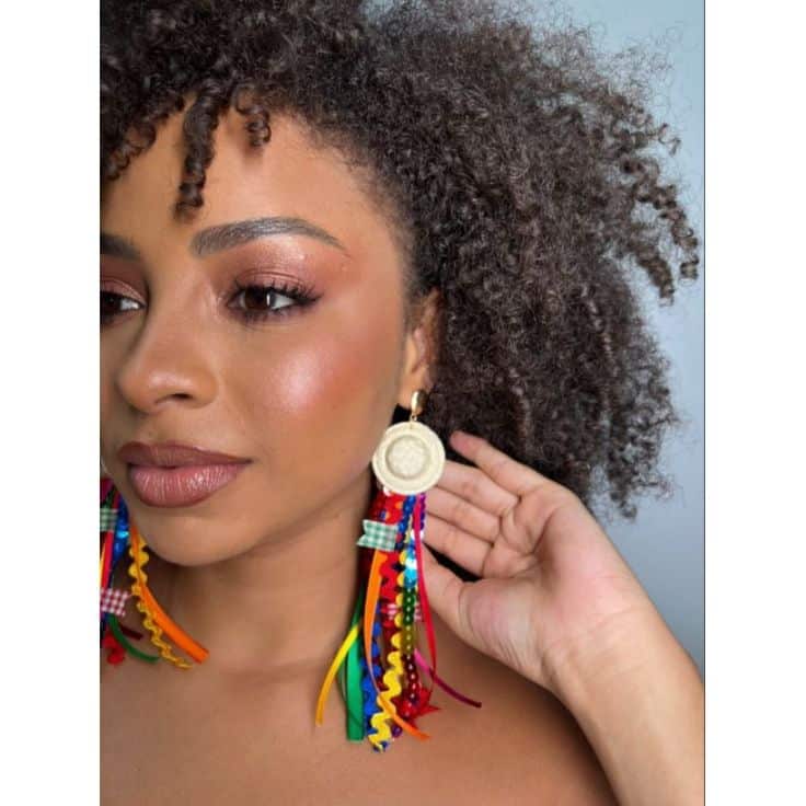 Brinco junino colorido com fitas e detalhes em palha, ideal para completar o look de festa junina 2025