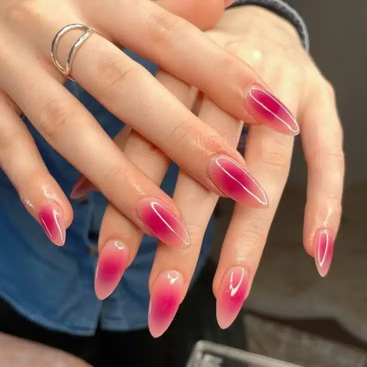 Unhas em estilo ombré com um gradiente rosa suave, exibindo formato alongado e elegante.