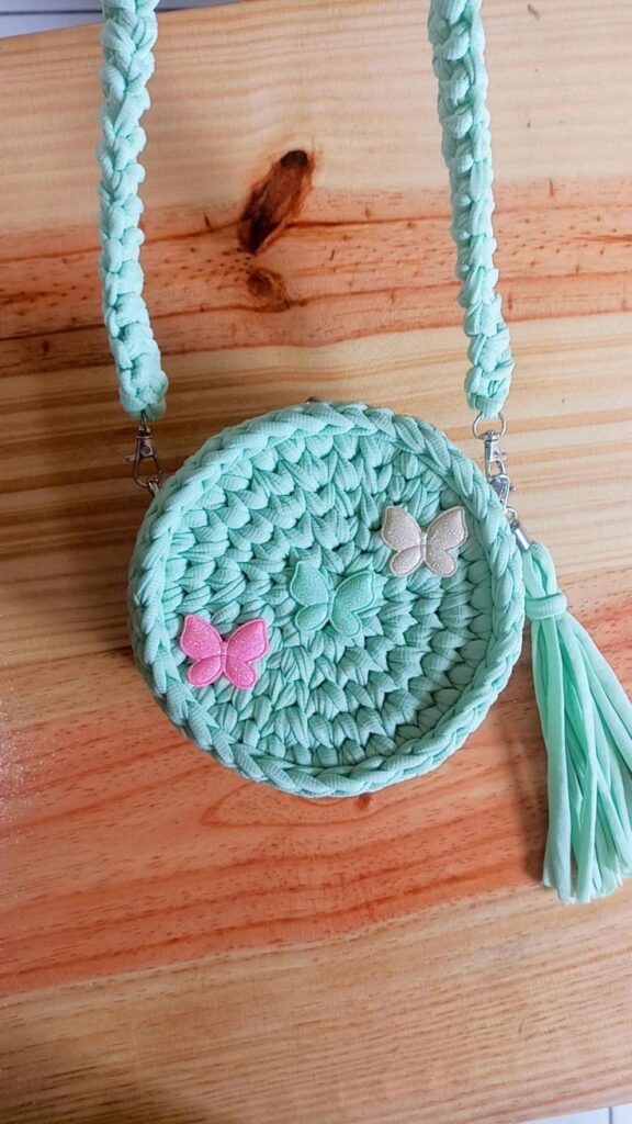Bolsa infantil de crochê com alça trançada e aplicação de borboletas