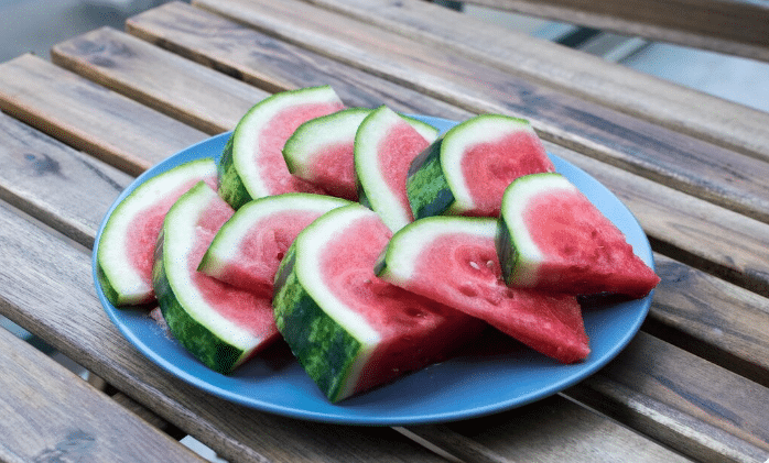 Fatias de melancia em prato azul sobre mesa de madeira
