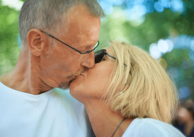 Casal trocando beijo com carinho e cumplicidade ao ar livre