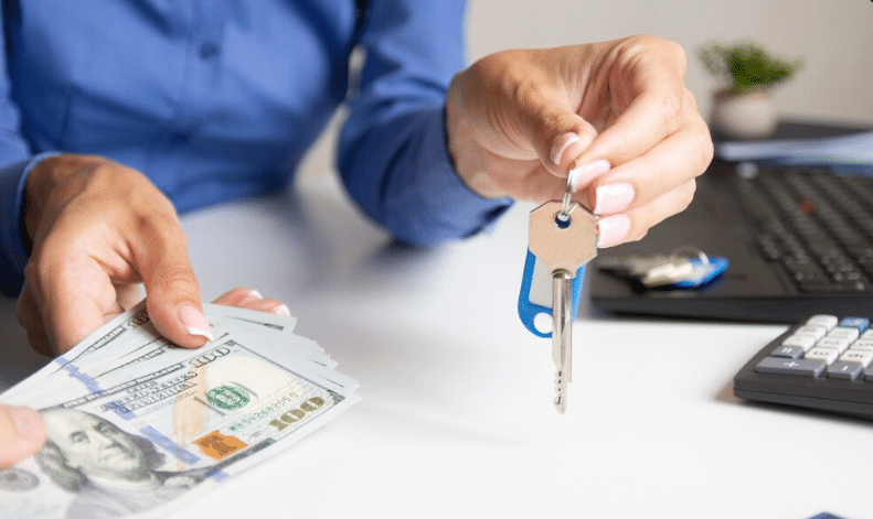 Pessoa entregando chave de imóvel com dinheiro e documentos sobre a mesa
