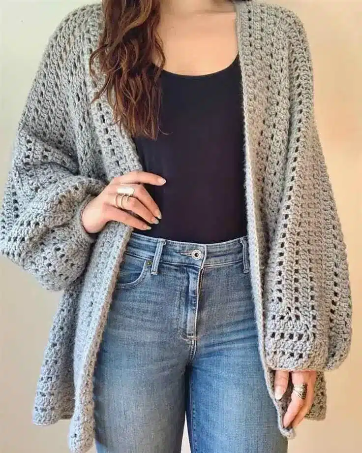Mulher usando cardigan de crochê cinza, perfeito para compor looks confortáveis e estilosos.