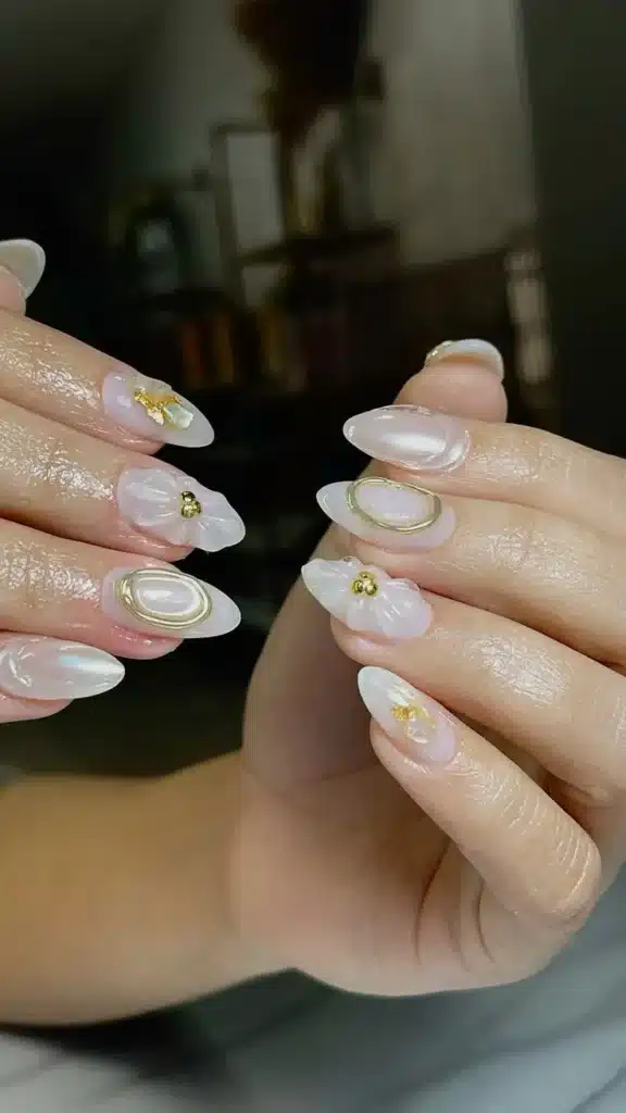 Design delicado de unhas com flores 3D e detalhes dourados.