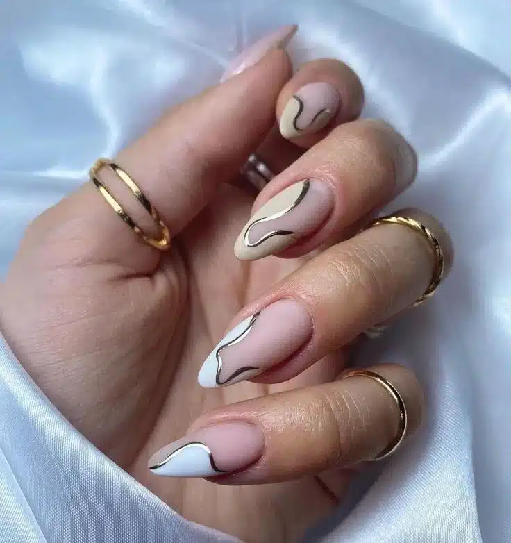 Unhas francesinha assimétrica com curvas elegantes e detalhes dourados, criando um visual moderno e criativo.