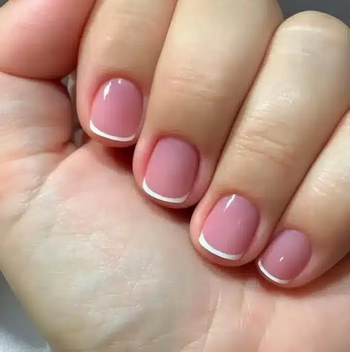 Francesinha delicada com esmalte neutro e pontas brancas.