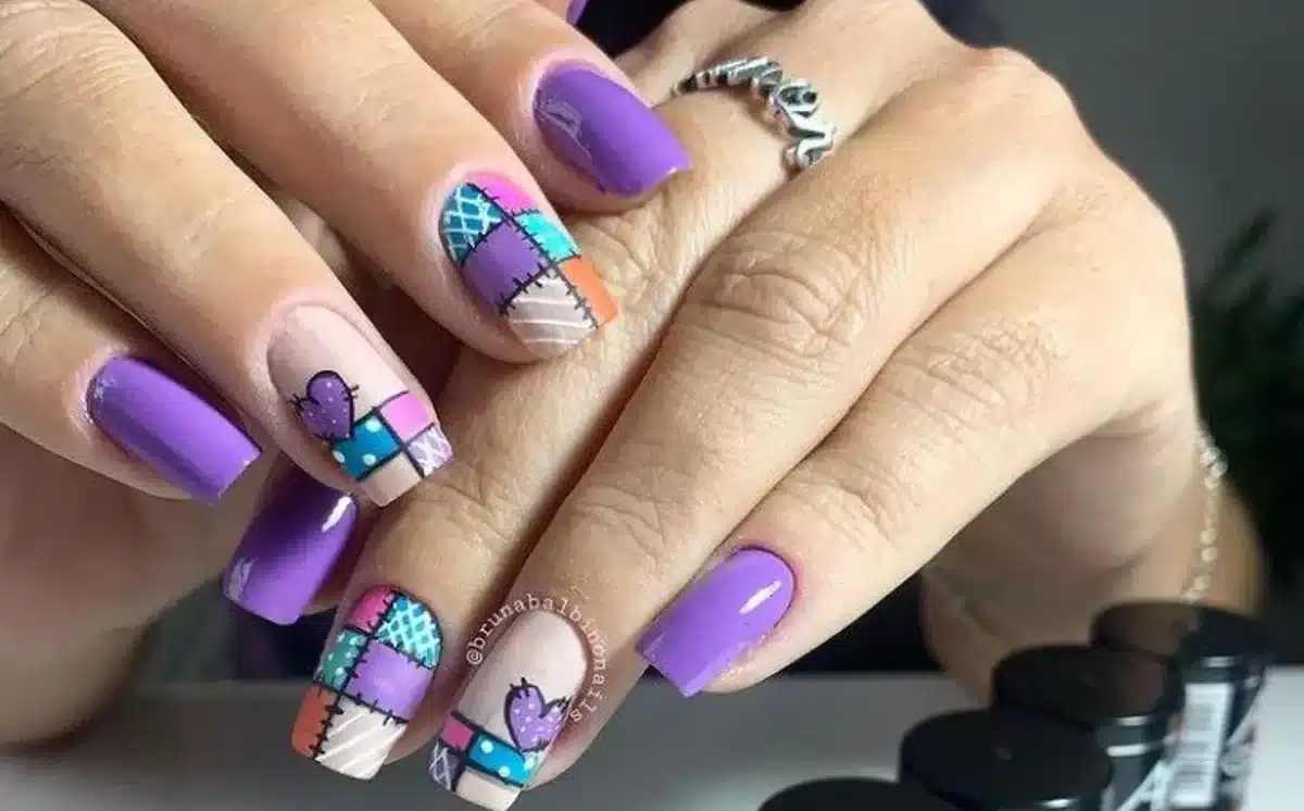 Unhas juninas com estampa patchwork colorida e esmaltes Anita, perfeita para o São João, com design vibrante em tons de roxo, rosa, azul e laranja.