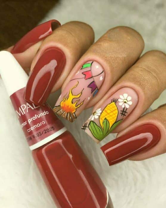 : Unhas de festa junina com elementos típicos como bandeirinhas, fogo e milho decorando as unhas, combinando com o clima de São João.