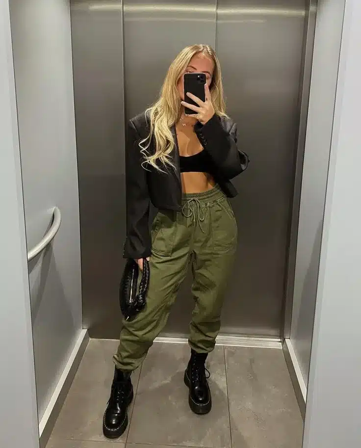 Look moderno com calça jogger verde, cropped preto e botas de plataforma, ideal para um visual ousado e confortável.