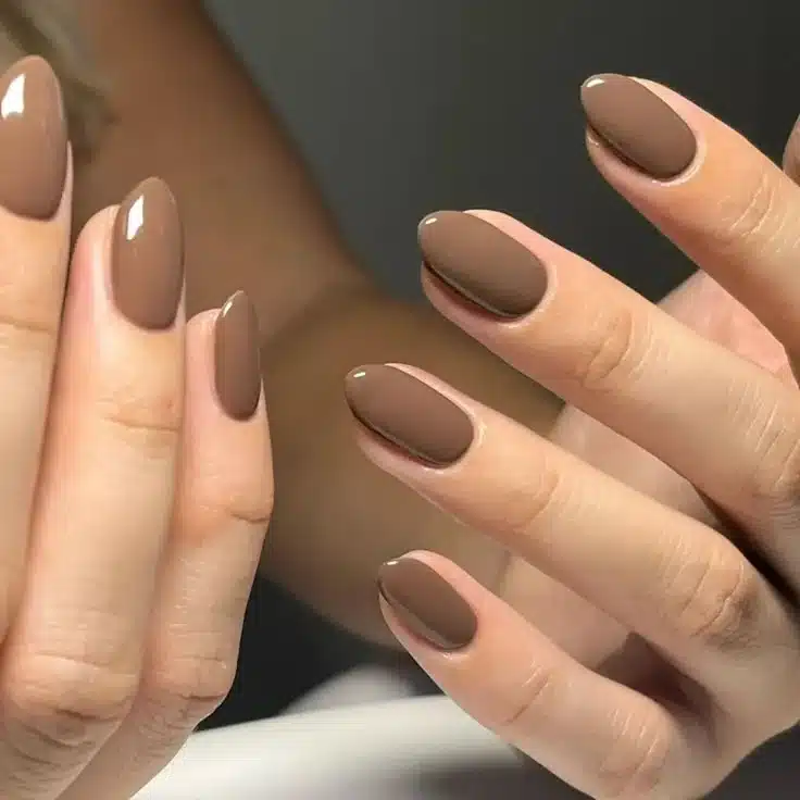 Unhas em tom marrom com café com leite para o inverno, com acabamento brilhante e formato oval.