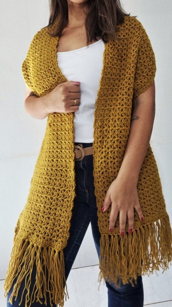 Mulher usando maxi cachecol de crochê amarelo com franjas em look casual