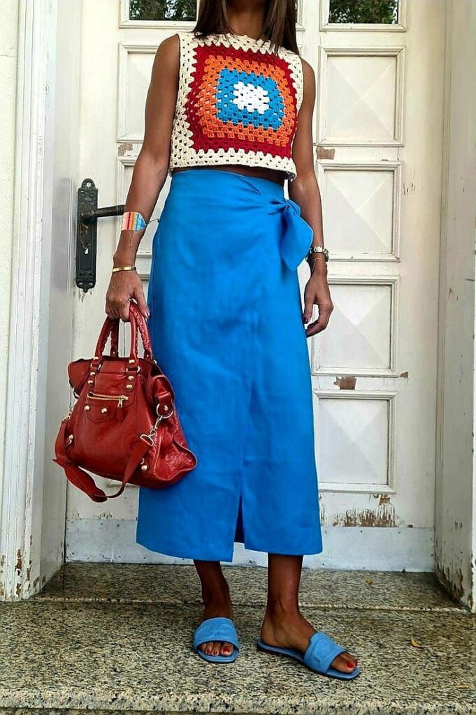Mulher com top de crochê colorido e saia azul em look moderno e vibrante