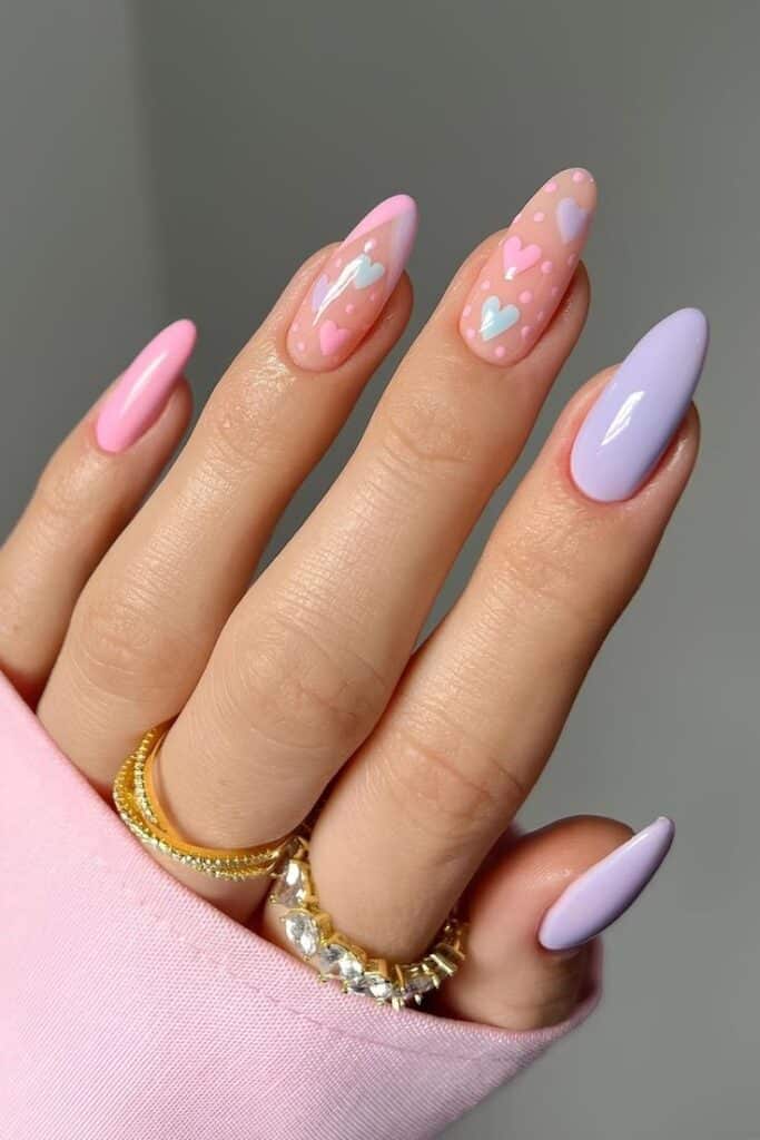 Unhas curvas com esmalte em tons pastel e nail art de corações