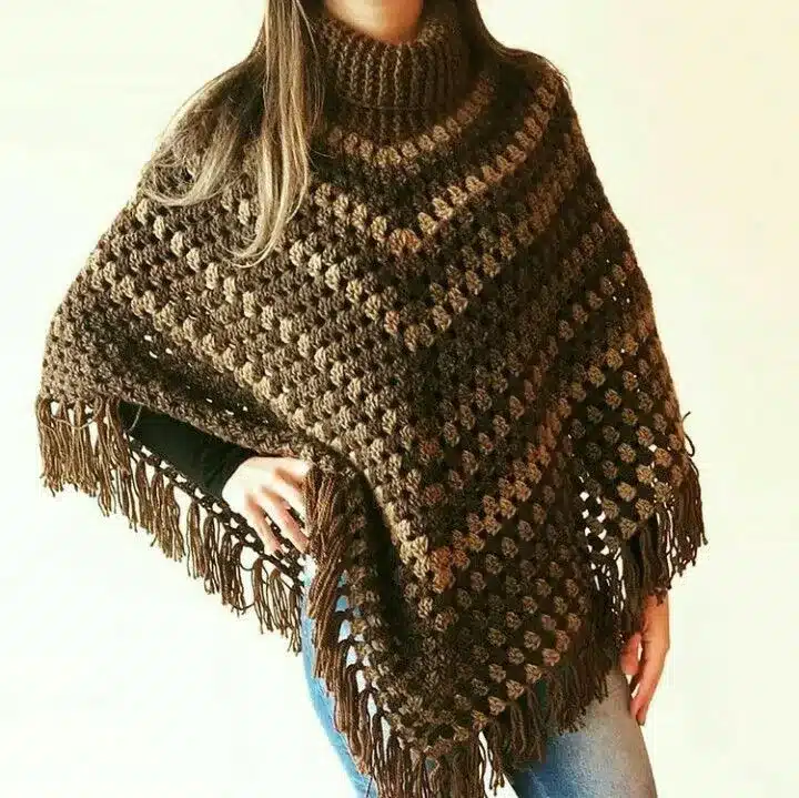 Mulher usando poncho de crochê marrom com franjas, perfeito para o inverno.