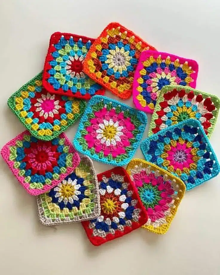 Granny squares coloridos de crochê com combinações vibrantes de cores como rosa, amarelo, azul e verde, formando quadrados harmônicos.