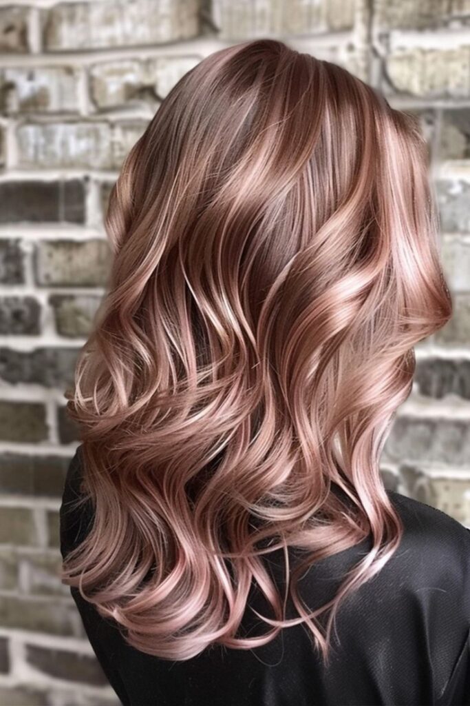 Mulher com cabelo em tons de rose gold, com ondas suaves e brilho iluminado, proporcionando um visual sofisticado e moderno.
