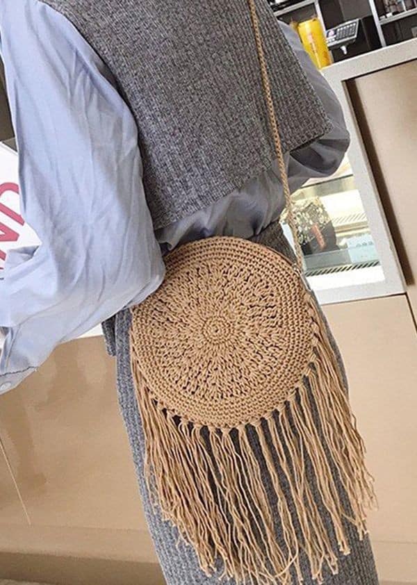 Bolsa de crochê redonda com franjas estilo boho pendurada no ombro