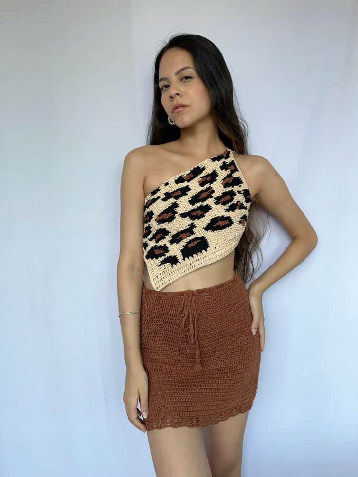 Look de crochê com estampa de animal, mostrando top frente única de onça e saia curta de crochê.