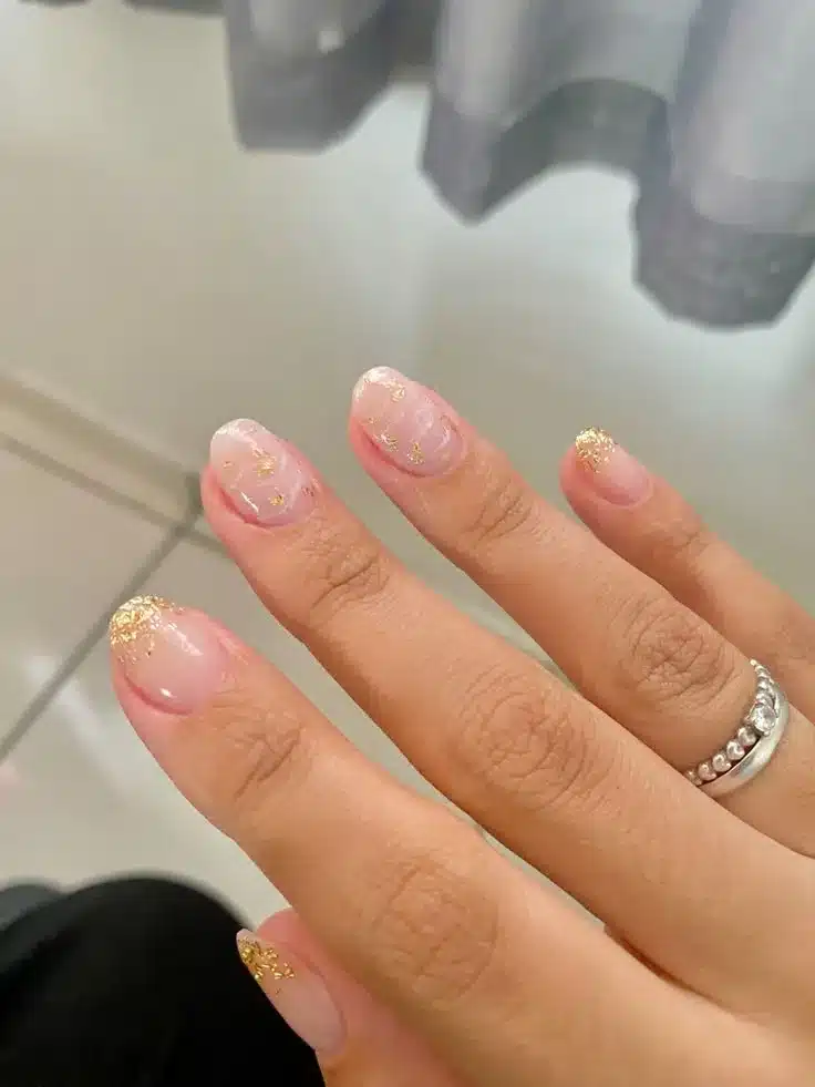Unhas delicadas com brilho dourado, perfeitas para um visual clean.