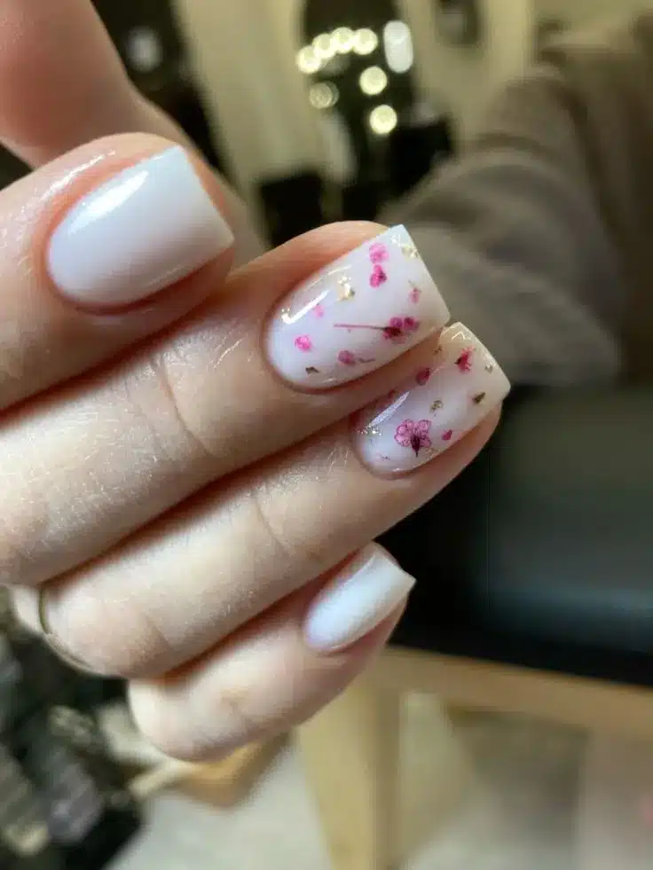 Unhas florais com detalhes em flores pequenas e douradas sobre base branca