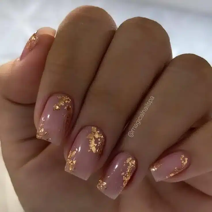 Unhas decoradas com folhas de ouro sobre base rosa suave, ideal para noivas