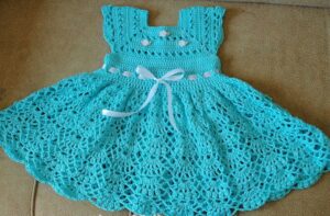 Vestido de crochê infantil azul com detalhes delicados e fita branca