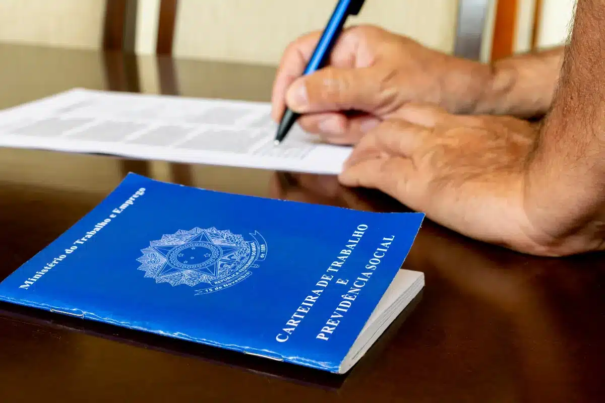 Carteira de Trabalho e assinatura de contrato em mesa.