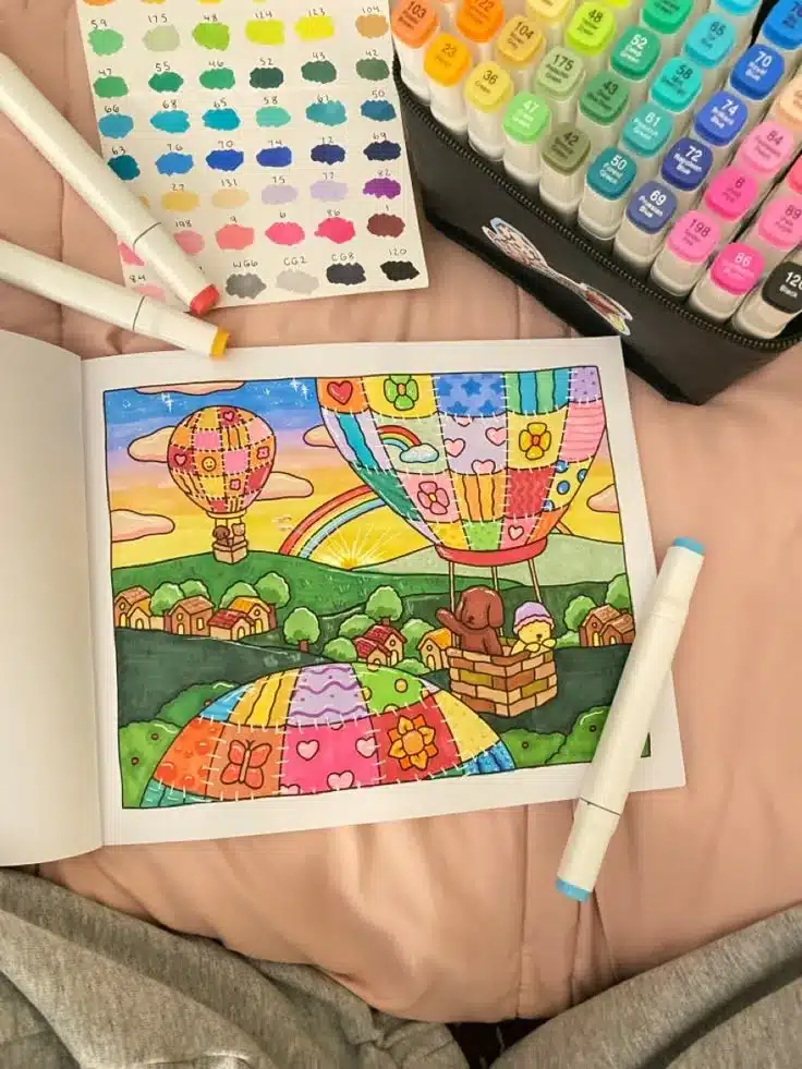 Ilustração colorida de balões de ar quente com casas e flores, usando canetas coloridas.