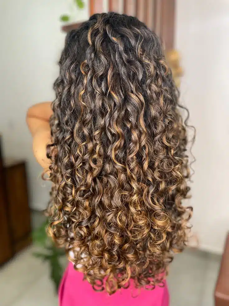 Cabelos cacheados soltos com cachos bem definidos e volumosos, perfeitos para festas e dança.