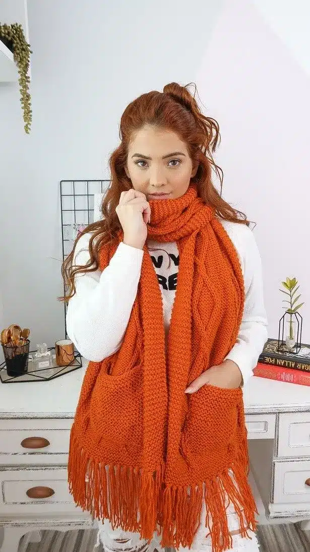 Mulher usando cachecol de crochê terracota com franjas e bolsos