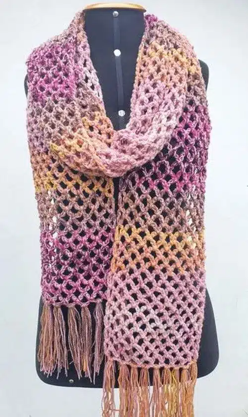 Cachecol de crochê com franjas coloridas em tons de rosa, roxo e laranja, ideal para aquecer no inverno