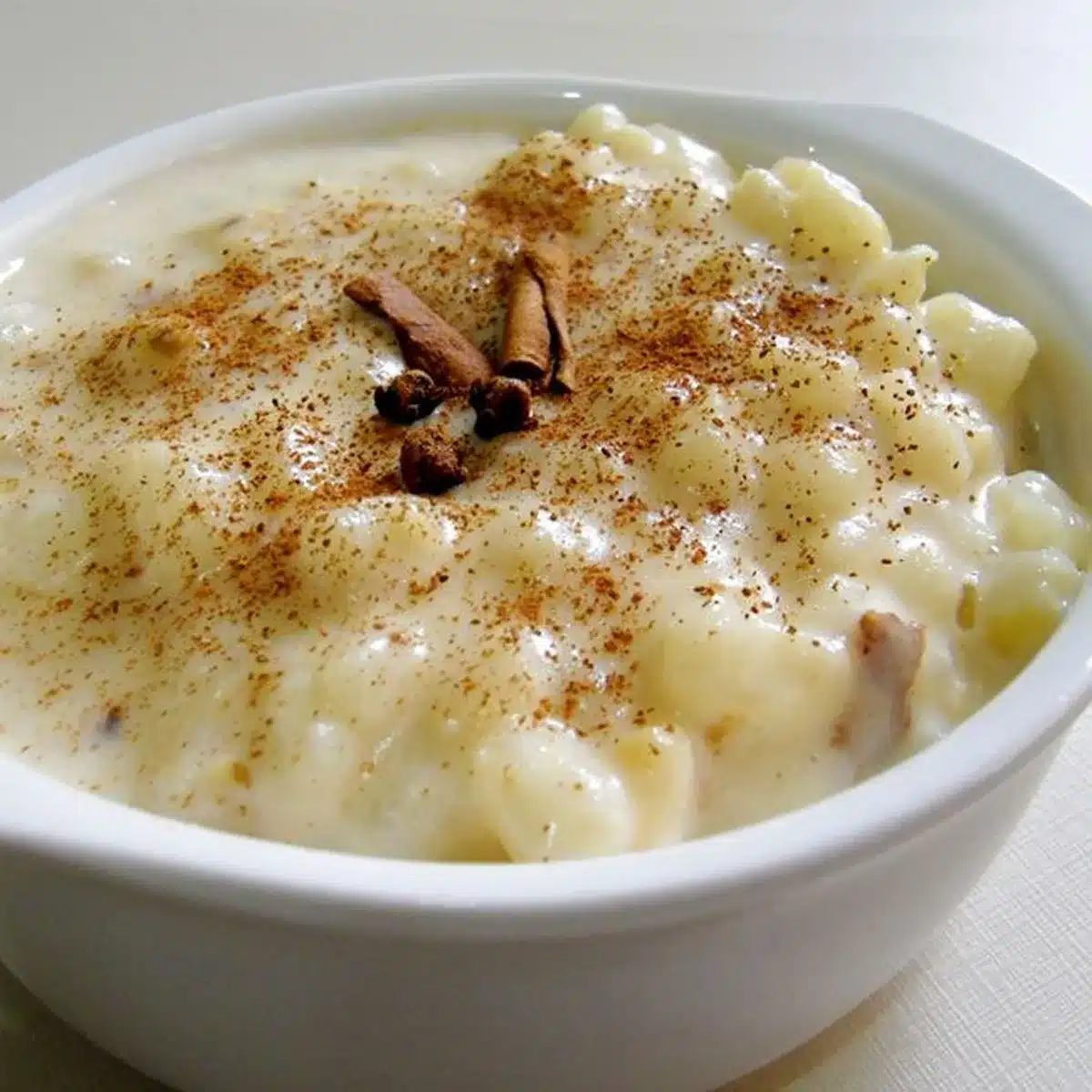 Canjica com leite condensado sendo preparada, com canela em pau e polvilho de canela por cima.