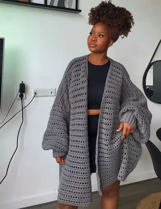 Mulher usando cardigã de crochê cinza com modelagem clássica e mangas amplas