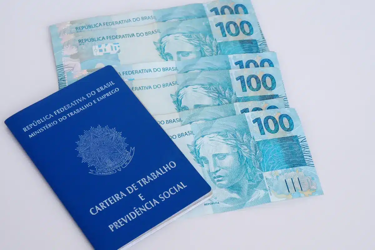 Carteira de Trabalho e notas de 100 reais representando direitos trabalhistas