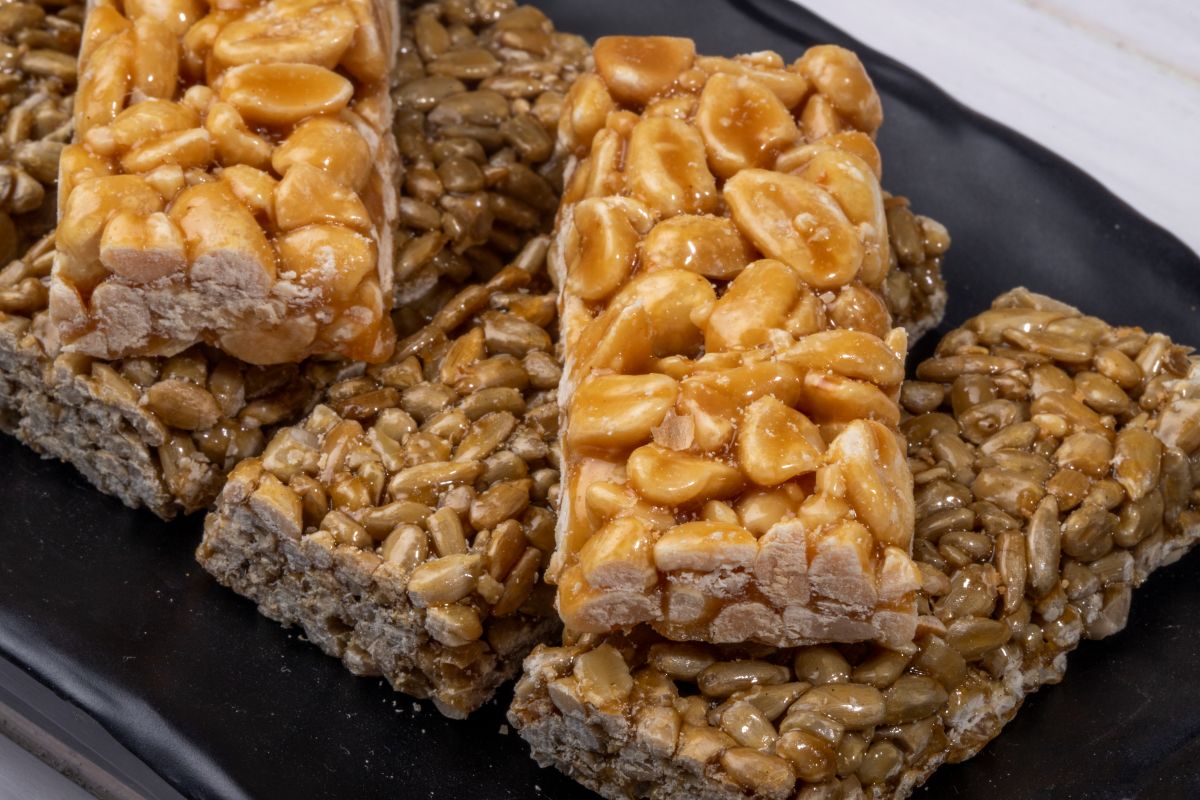 Barrinhas de pé-de-moleque com amendoim e sementes de girassol servidas em prato preto