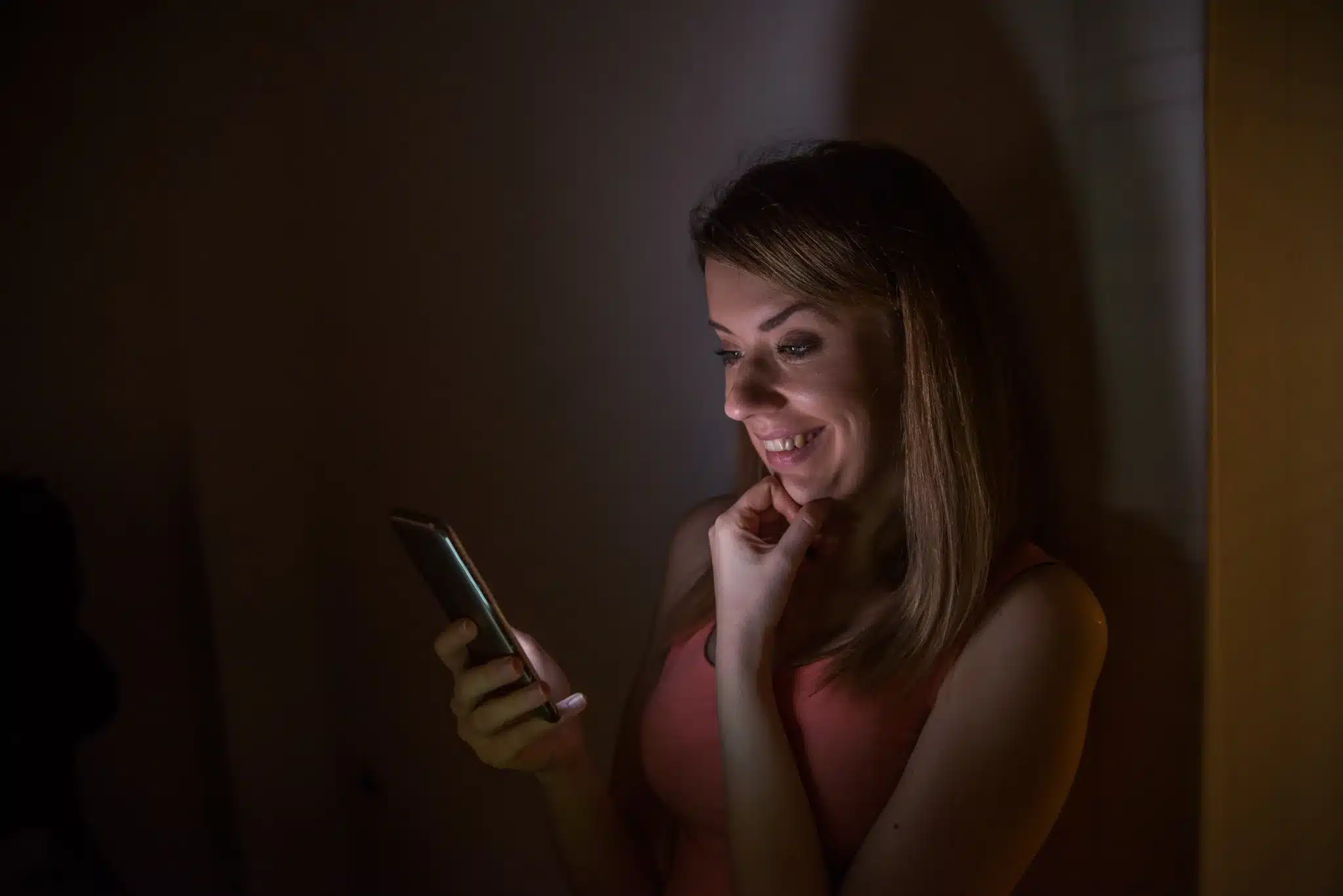 Mulher sorrindo ao ler mensagem de boa noite no celular