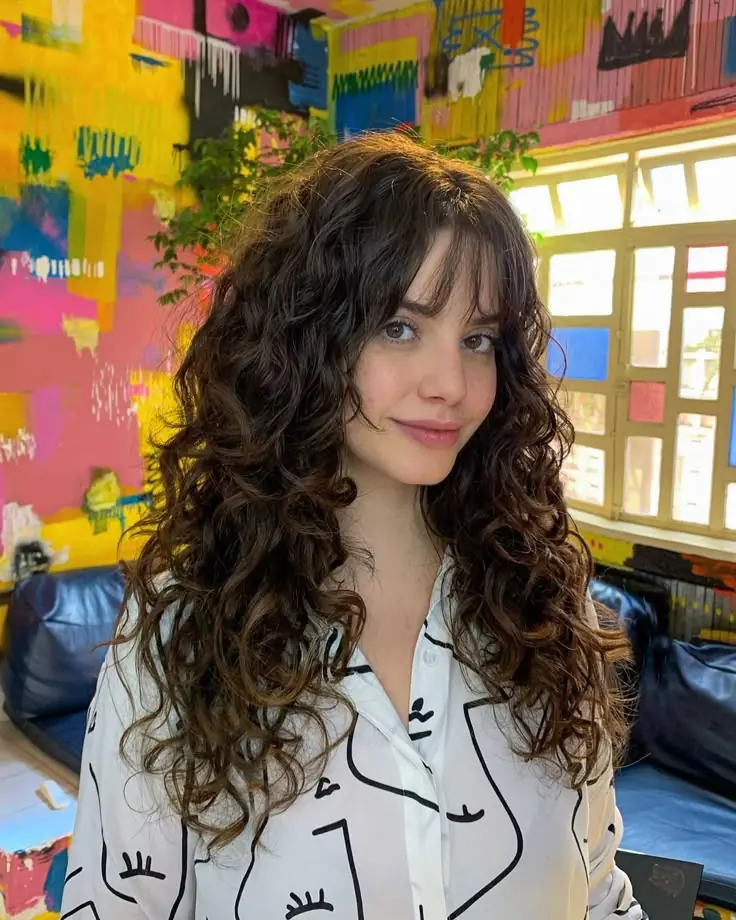 mulher com cabelo cacheado longo e corte shaggy em ambiente colorido