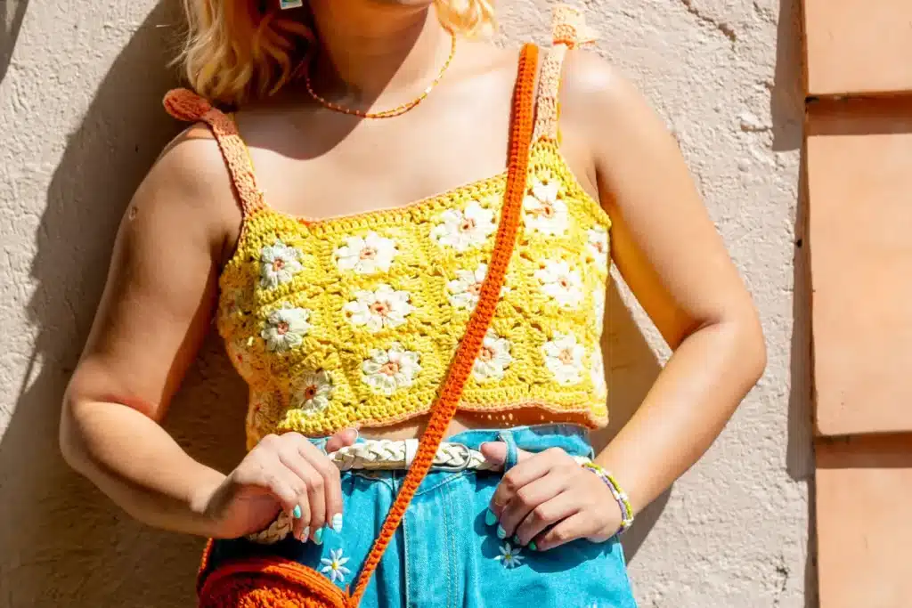 cropped de crochê Blusa de crochê amarela com flores coloridas, detalhes em laranja, e acessórios combinando em um look casual e vibrante.