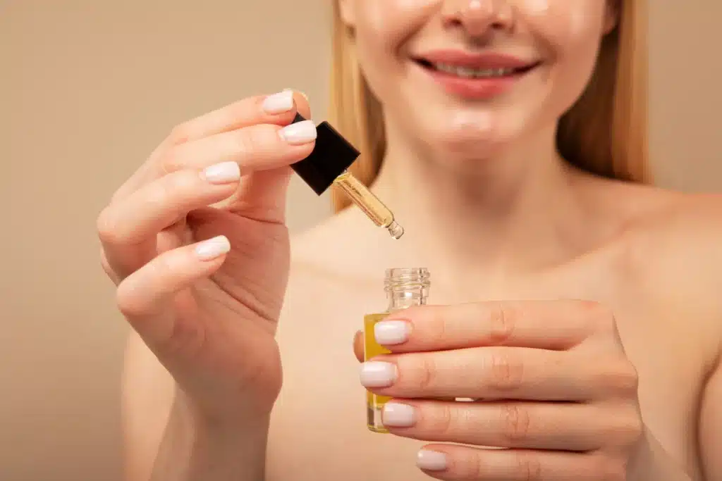 Mãos femininas aplicando óleo para unhas e cutículas após remoção do esmalte