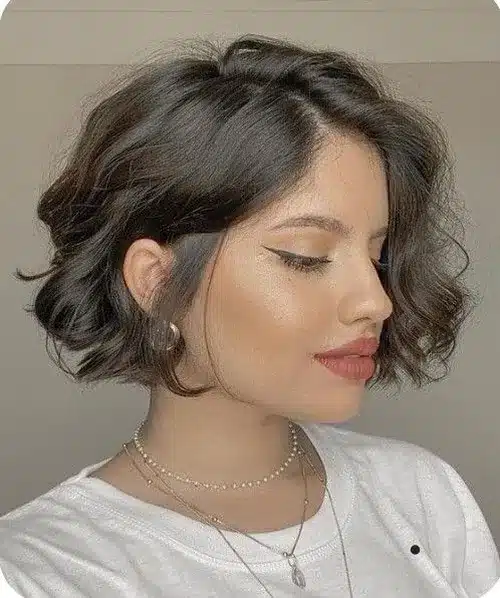 Mulher com cabelo curto e ondas soltas, visual glamouroso e sofisticado.