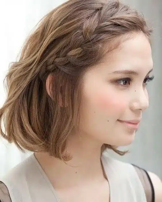 Mulher com cabelo curto e trança lateral, visual romântico e elegante.