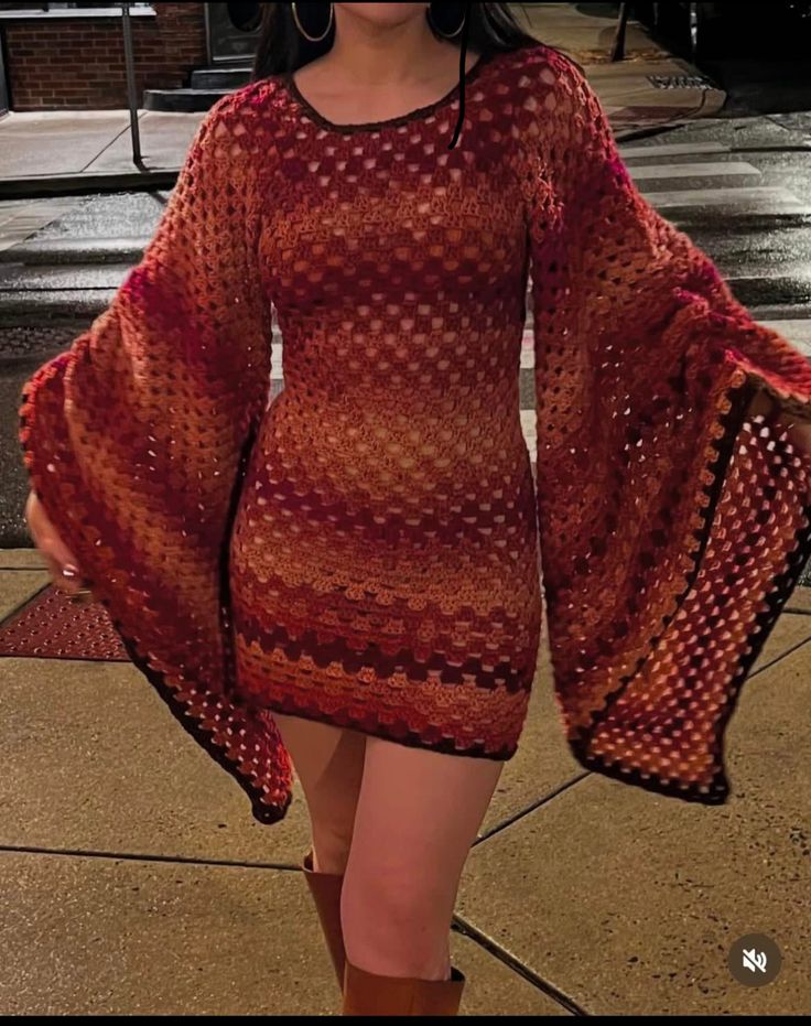 Vestido de crochê em tons quentes com mangas largas, estilo moderno.